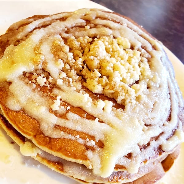 Stack of Corner Post Diner pancakes topped with white icing and crumbly streusel.