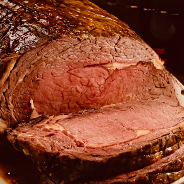 Close-up of a perfectly cooked, sliced prime rib roast with a rich brown crust.