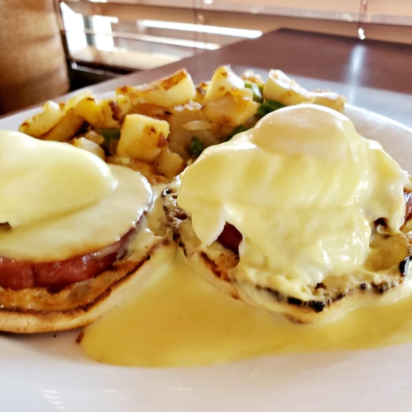 Eggs Benedict with Canadian bacon, hollandaise sauce, and a side of home fries at Corner Post Diner.
